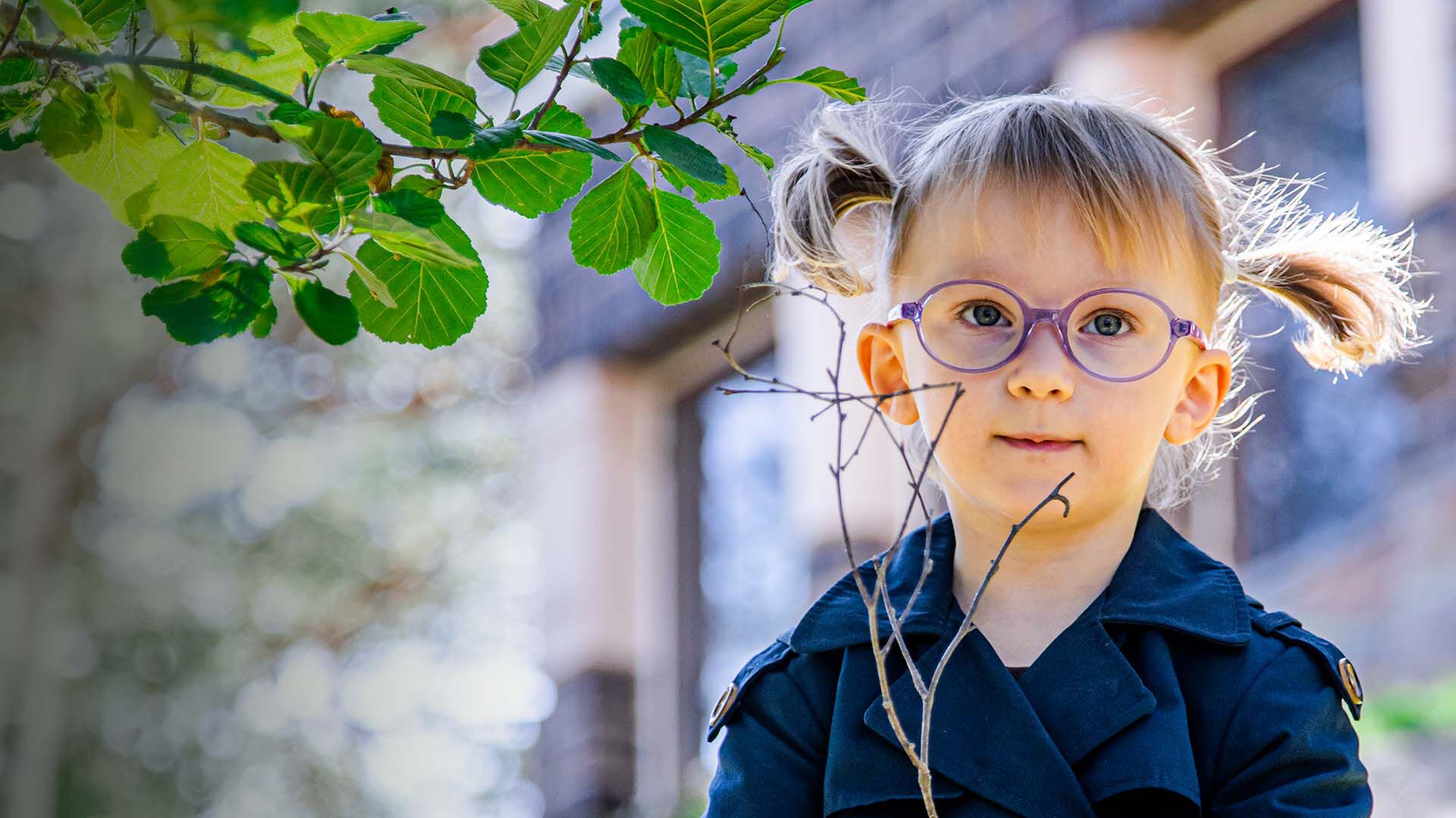 Saparopäinen pikkulapsi ulkona oksa kädessä